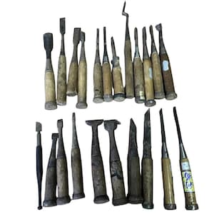 Peut inclure: Une collection de vingt ciseaux à bois et outils de sculpture assortis, dotés de manches en bois patiné et de lames en métal de formes et tailles variées. Certains outils ont des viroles métalliques et un manche porte une étiquette jaune avec du texte japonais.
