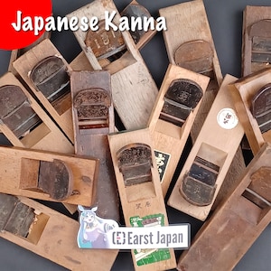Op de afbeelding: Een verzameling Japanse handvlakken, bekend als kanna, gemaakt van hout met metalen messen. De vlakken zijn in verschillende maten en stijlen, en sommige hebben Japanse karakters.