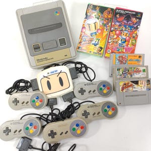 May include: A Nintendo Super Famicom console with game cartridges, controllers, and a multi-tap adapter. The console is gray and beige, with the Super Famicom logo. Game boxes feature colorful illustrations.
