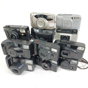 Könnte beinhalten: Eine Sammlung verschiedener Vintage-Kompaktfilmkameras. Die Kameras sind in Schwarz-, Silber- und Grautönen gehalten und weisen sichtbare Objektive, Blitze und Markennamen wie Fuji und Sakura auf. Einige Kameras haben Preisschilder.