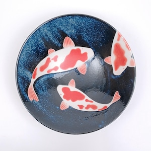 Puede incluir: Un cuenco de cerámica azul con un diseño de peces koi blancos y rojos. El cuenco tiene un esmalte azul moteado.