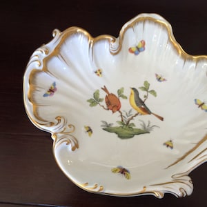 May include: A white porcelain shell-shaped dish with gold trim and a painted scene of birds and butterflies.