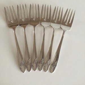 May include: Set of eight silver-plated forks with ornate floral designs on the handles.