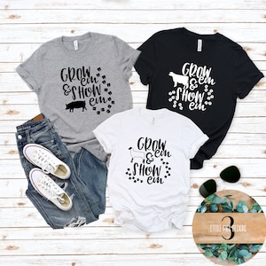 Peut inclure: Trois t-shirts avec des silhouettes d'animaux diff&eacute;rentes et le texte "Grow 'em & Show 'em" imprim&eacute; en noir. Les t-shirts sont gris, noir et blanc.