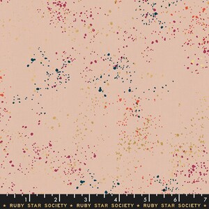 May include: A pink fabric with a scattered pattern of gold, red, and blue dots. The fabric has a subtle shimmer.