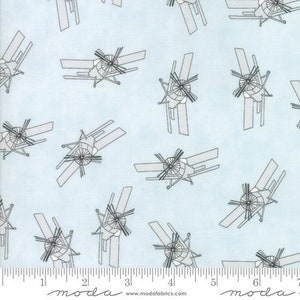 May include: A light blue fabric with a repeating pattern of black and gray airplanes. The airplanes are stylized and have a propeller in the front. The fabric has a ruler with the word "moda" printed on it.