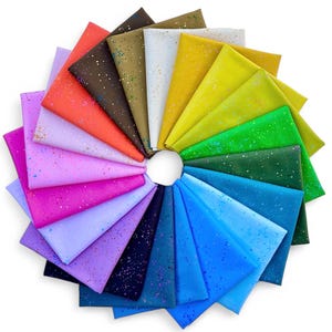 Op de afbeelding: Een verzameling van 20 stoffen vierkanten in verschillende kleuren met een gespikkeld patroon. De vierkanten zijn in een cirkel gerangschikt, waarbij de kleuren van donker naar licht overgaan.