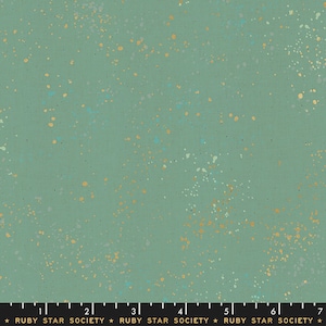 May include: A green fabric with a speckled pattern of gold, blue, and white dots. The fabric is marked with a ruler and the text "RUBY STAR SOCIETY".