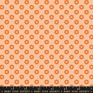 Może przedstawiać: Brzoskwiniowa tkanina z powtarzającym się wzorem pomarańczowych kwiatów. Każdy kwiat ma centralne koło i płatki. Tkanina nadaje się do pikowania, szycia lub innych projektów rzemieślniczych. Tekst "RUBY STAR SOCIETY" jest wydrukowany na dole.