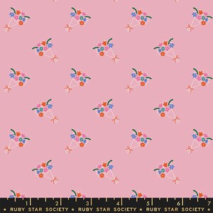 May include: Pink fabric with a repeating pattern of colorful bouquets of flowers. The bouquets are tied with a white ribbon and have green leaves. The fabric is marked with a ruler in inches.