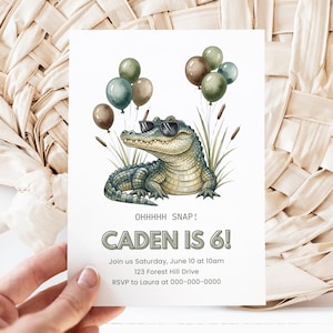 May include: A birthday invitation featuring a cartoon alligator wearing sunglasses and holding balloons. The text reads "OHHHHH SNAP! CADEN IS 6!" with event details below. The invitation is held by a hand.