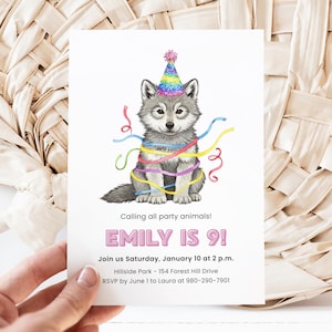 Puede incluir: Una invitación de cumpleaños con una ilustración en acuarela de un cachorro de lobo gris con un gorro de fiesta arcoíris y envuelto en serpentinas de colores. El texto dice "EMILY IS 9!" y detalles de la fiesta.