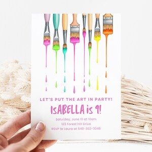 Op de afbeelding: Een witte uitnodigingskaart met kleurrijke penselen en druipende verf. De tekst luidt "LET'S PUT THE ART IN PARTY! ISABELLA is 9!" met evenementdetails. De kaart wordt door een hand vastgehouden.