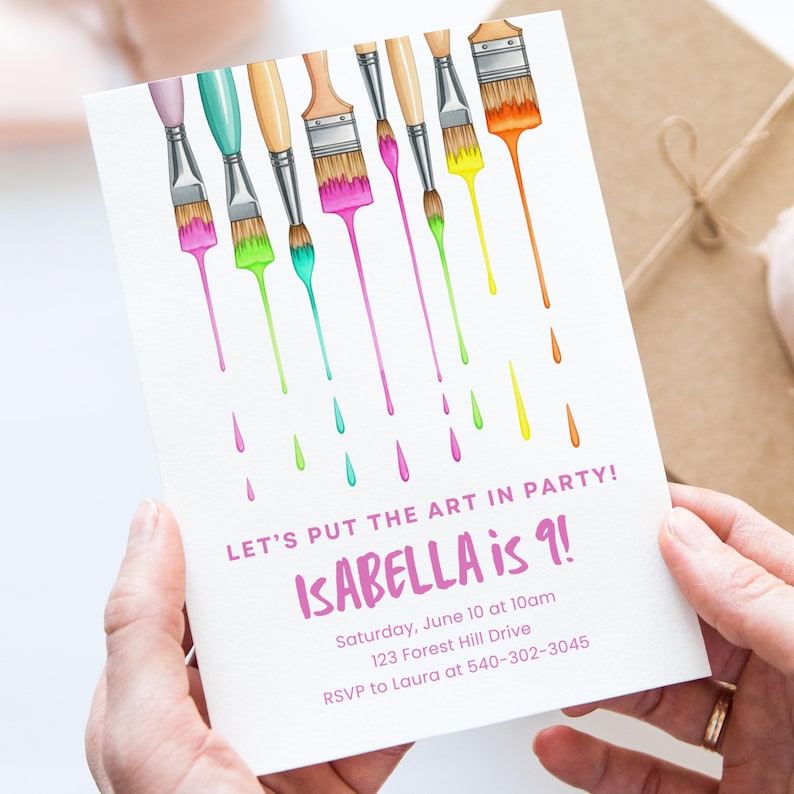 Op de afbeelding: Witte uitnodigingskaart met kleurrijke penselen en druipende verf. Tekst luidt "LET'S PUT THE ART IN PARTY! ISABELLA is 9!" met evenementdetails. De kaart wordt door handen vastgehouden.