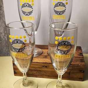 May include: Four clear glass goblets with a gold rim and a black and gold logo that reads "Pabst's Crystal" with yellow dots around the logo.