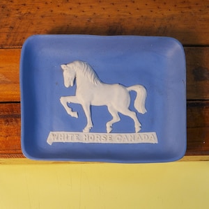 May include: A blue ceramic trinket tray with a white horse design and the text "White Horse Canada".