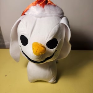 May include: White plush toy with a black stitched smile and eyes. The toy is wearing a red and white Santa hat.