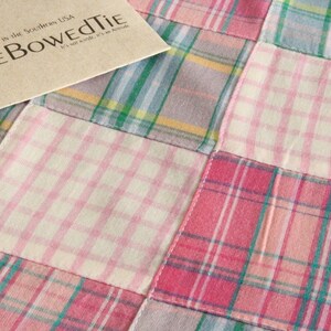 May include: A close-up of a patchwork fabric featuring a variety of plaid patterns in pink, white, green, and yellow. A tan card with the text "The Bowed Tie" and an anchor logo is in the upper left corner. The fabric is handcrafted in the Southern USA.