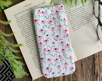 May include: A white eyeglass case with a floral pattern of pink flowers and green stems on a white background. The case has a white button closure.