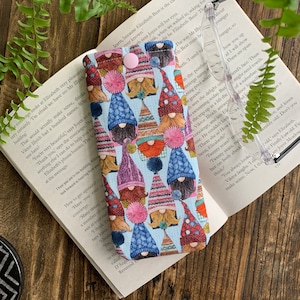 May include: A blue and white fabric glasses case with a repeating pattern of gnomes wearing colourful hats. The gnomes have white beards and rosy cheeks.