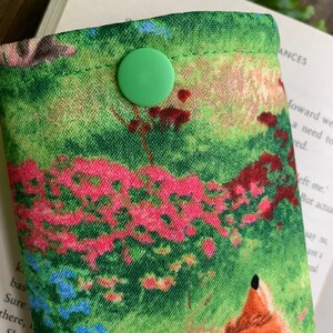 Puede incluir: Una bolsa de tela verde con cierre de bot&oacute;n verde. La bolsa tiene un estampado floral colorido con un dise&ntilde;o de zorro.