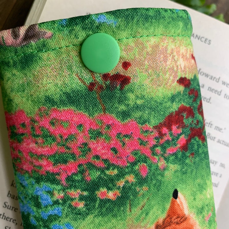 Puede incluir: Una bolsa de tela verde con cierre de bot&oacute;n verde. La bolsa tiene un estampado floral colorido con un dise&ntilde;o de zorro.