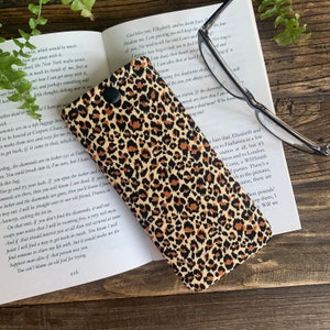 May include: A leopard print glasses case with a black button closure. The case is made of fabric and has a soft, plush lining to protect your glasses.