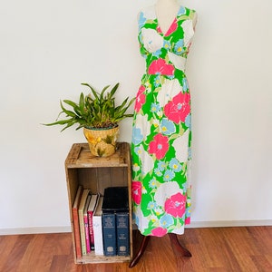 May include: A sleeveless maxi dress with a V-neckline and a floral print in shades of pink, blue, and green. The dress is on a white mannequin and has a white background.