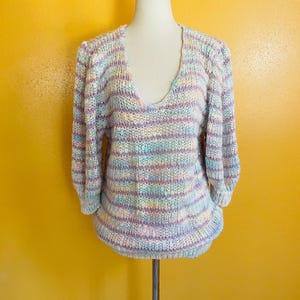 May include: A pastel striped knit sweater with a v-neck and puffed sleeves.