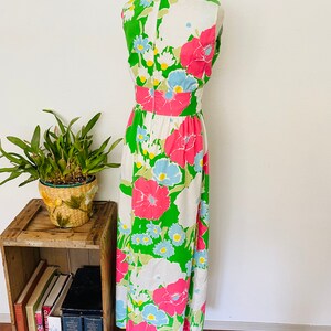 May include: A white, green, pink, and blue floral print maxi dress with a sleeveless design. The dress has a fitted bodice and a flowing skirt.
