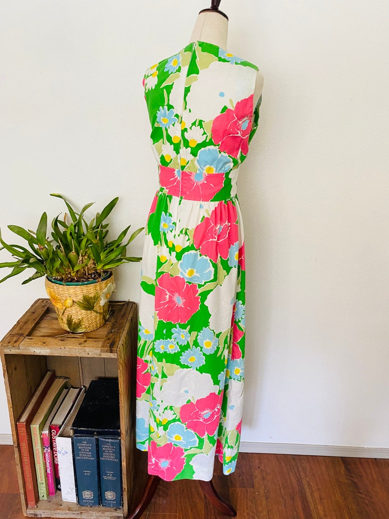 May include: A white, green, pink, and blue floral print maxi dress with a sleeveless design. The dress has a fitted bodice and a flowing skirt.
