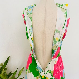 May include: A white dress with a green, pink, and blue floral print. The dress has a sleeveless design and a zipper down the back.