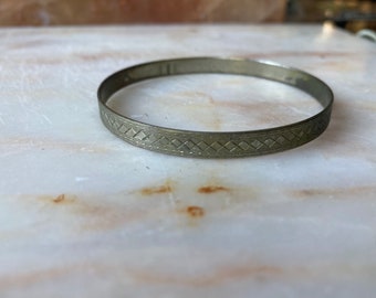 Op de afbeelding: Een zilveren armband met een geometrisch patroon.
