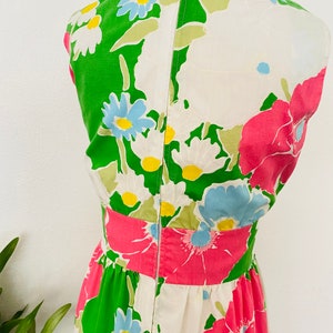May include: A white dress with a green, pink, and blue floral print. The dress has a sleeveless design and a back zipper closure.