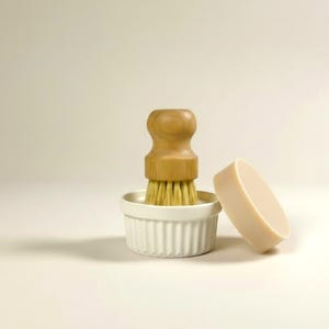 May include: A white ceramic mug with a black handle and the text "But First, Coffee" in a bold, black font. The mug is set against a blurred background, suggesting a cozy setting.