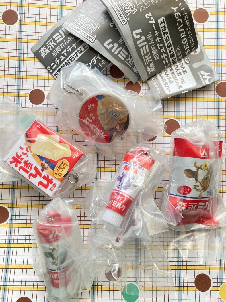 May include: A collection of miniature Japanese food items, including milk cartons, ice cream bars, and a tube of milk, all in their original packaging. The items are red, white, and blue, and some have Japanese text.