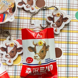 May include: A white ceramic mug with a black handle and the text "But First, Coffee" in a black, bold font. The mug is on a white surface. The mug is approximately 4 inches tall.