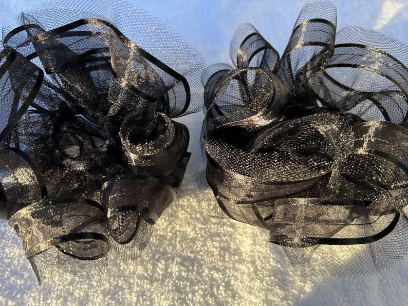 May include: Two black tulle bows with a shimmery finish. The bows are made of a soft, delicate material and are perfect for adding a touch of elegance to any occasion.
