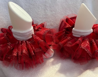 May include: A pair of white socks with red tulle ruffles around the top. The ruffles have a sparkly finish.