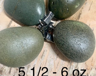 May include: Four smooth, dark green river rocks, each about 5 1/2 to 6 ounces, arranged in a circle on a light brown wooden surface.