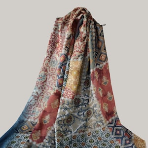 May include: A lightweight scarf featuring a patchwork design with various floral, geometric, and paisley patterns in shades of terracotta, muted blue, mustard yellow, and cream. The fabric displays a repeating motif across the entire surface.