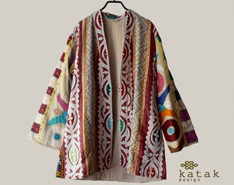 May include: A colorful, patchwork-style jacket with a long, open front. The jacket is made of a variety of fabrics and features intricate embroidery in shades of red, blue, green, and yellow.