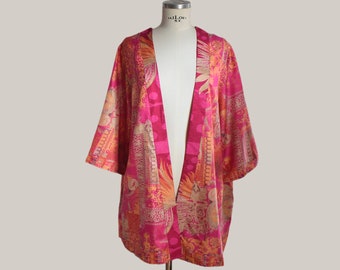 Pode incluir: Um quimono estampado em rosa e laranja com um decote em V profundo. O quimono tem um design geométrico e floral.