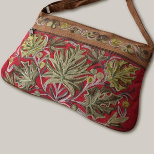 Maroon suede crossbody bag with floral embroidery, long strap and zipper closure, ideal for everyday use, comfortable and lightweight