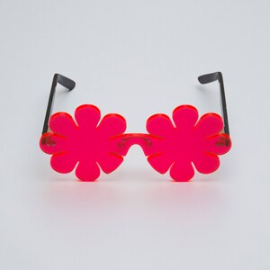 May include: A pair of pink flower-shaped sunglasses with black frames.