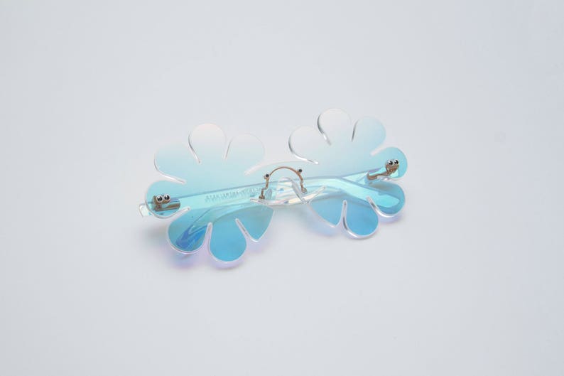 May include: Blue iridescent flower-shaped sunglasses with a silver metal frame.
