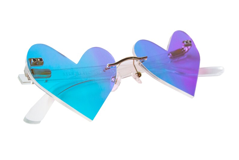 May include: Heart-shaped sunglasses with a blue and purple iridescent lens. The frame is white and the arms are clear.