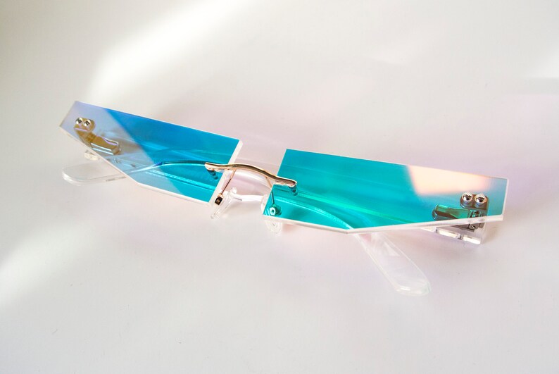 Puede incluir: Un par de gafas con montura transparente azul iridiscente y puente de metal plateado.