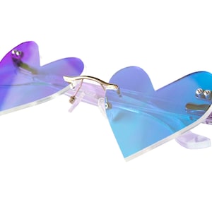 May include: Heart-shaped sunglasses with a iridescent blue and purple gradient lens. The frame is clear plastic with gold accents.