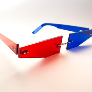Puede incluir: Un par de gafas de sol rojas y azules con un marco geom&eacute;trico. Las gafas de sol est&aacute;n hechas de pl&aacute;stico y tienen un dise&ntilde;o moderno.